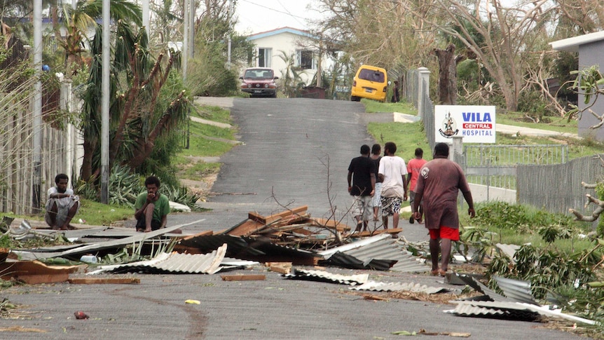 Local residents sit near debris after Cyclone Pam in Vanuatu