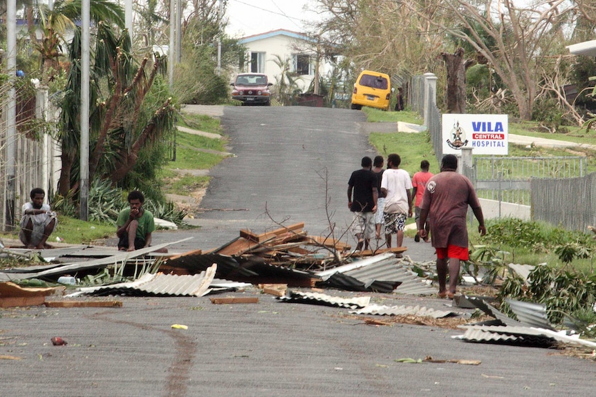 Local residents sit near debris after Cyclone Pam in Vanuatu