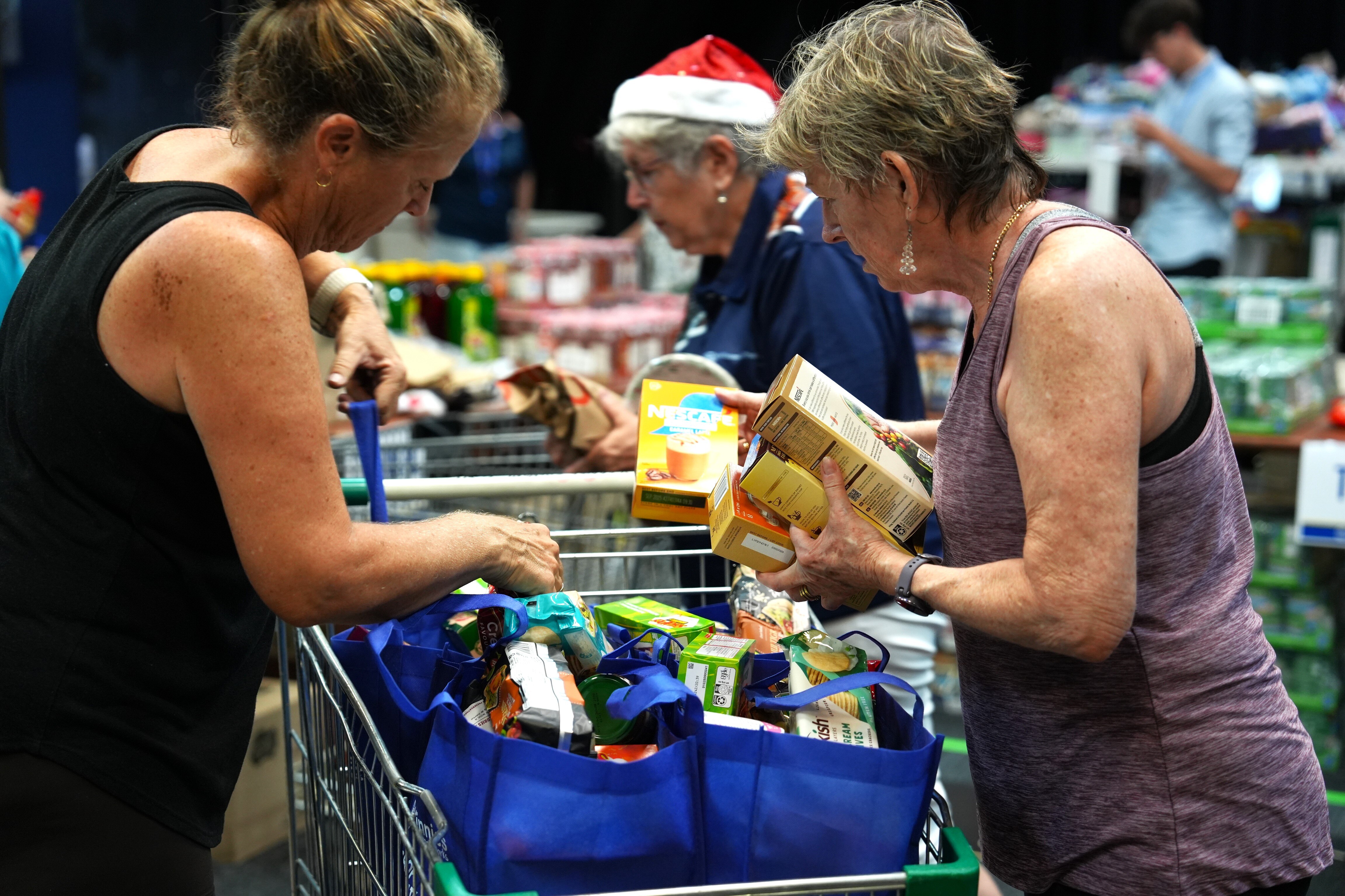 Three women, volunteers sorting through a pile of donated goods for the Vinnies hampers.