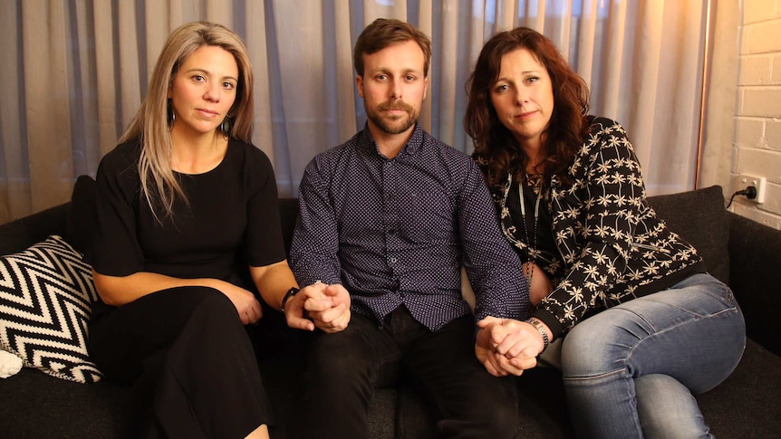 Murdered Melbourne woman Joy Rowley's children Nadine Power, Aaron Woolridge and Renee Woolridge sit together holding hands.