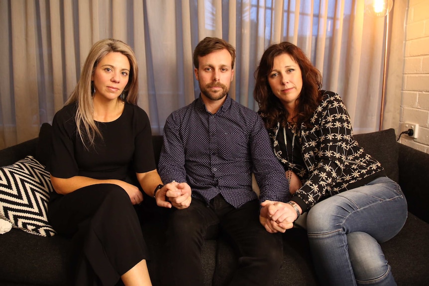 Murdered Melbourne woman Joy Rowley's children Nadine Power, Aaron Woolridge and Renee Woolridge sit together holding hands.