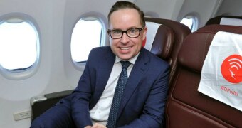 Alan Joyce sits inside a plan on a chair