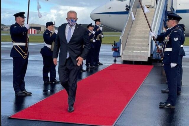 Prime Minister Scott Morrison walks on a red carpet flanked by military personnel at an airport as shown on Instagram.