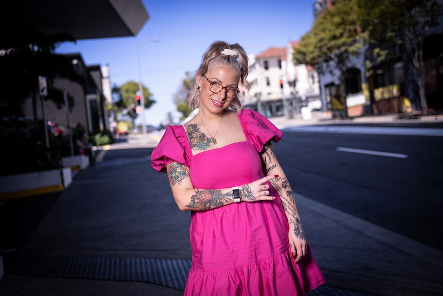 A tattooed woman in a pink dress 