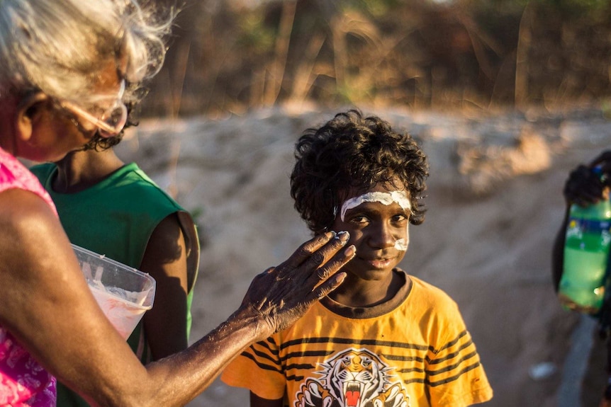 A woman paints a child's face