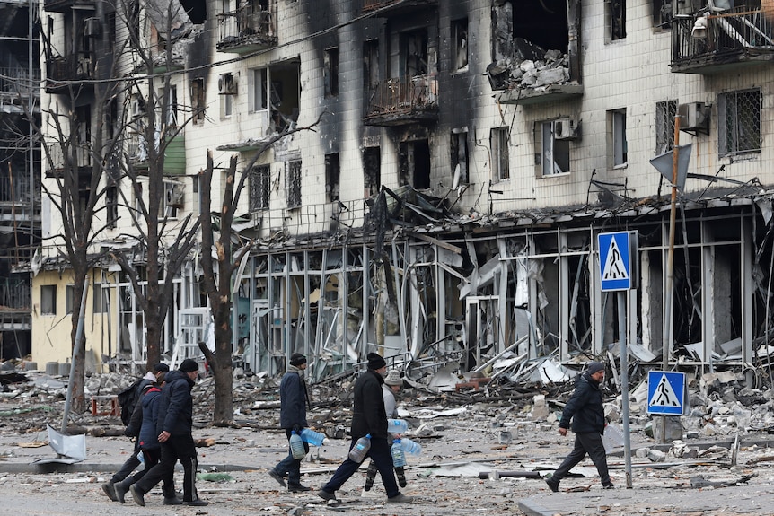 People walked past damaged buildings destoryed by military strikes. 