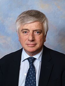 A white man with grey hair wearing a black suit