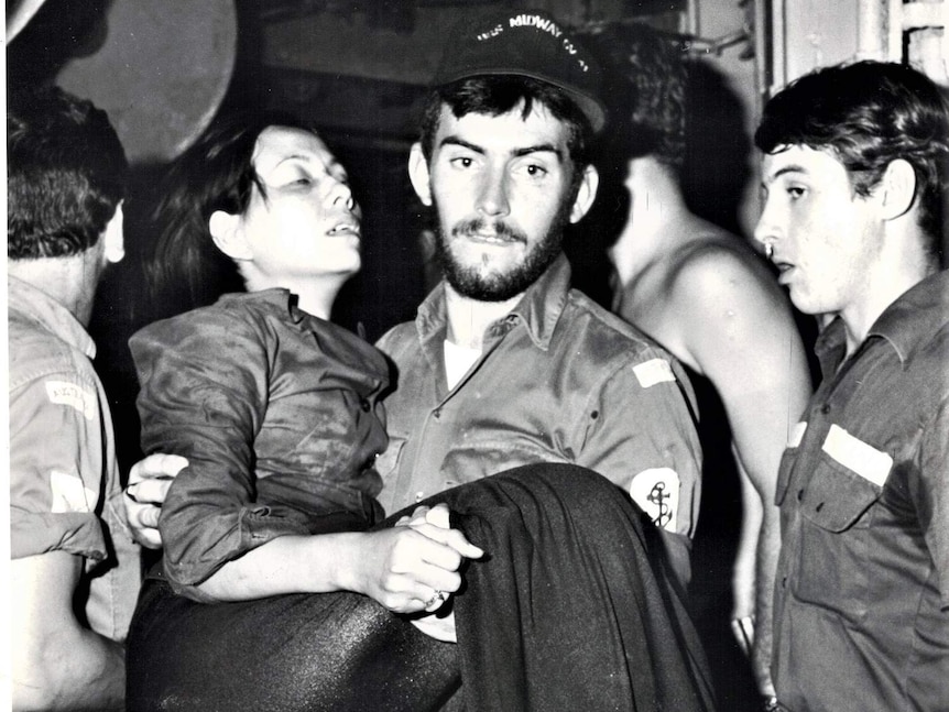 A navy crew member helps rescue a Vietnamese refugee in 1981 on a HMAS boat.