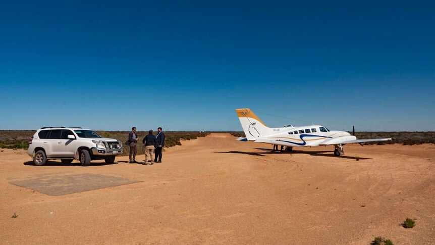 People getting into a car after landing a plane at a remote airstrip.  