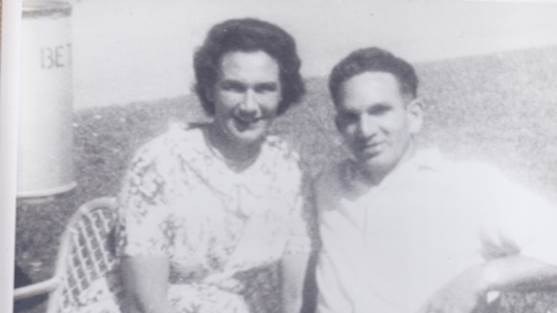 A black and white photo of a couple sitting together, smiling.