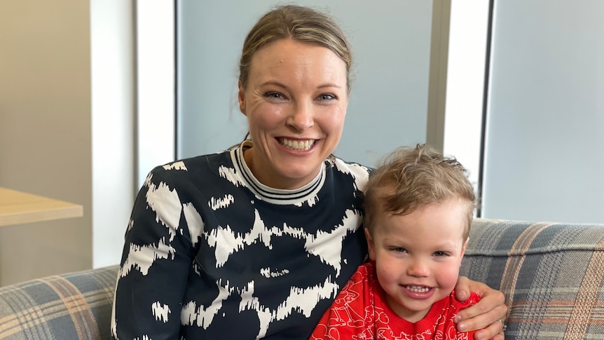 A smiling woman in a black and white jumper with a smiling boy wearing a red jumper.