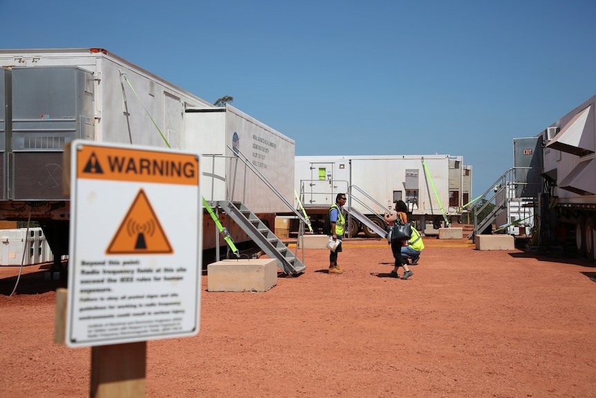 A futuristic looking worksite with shipping containers on red earth.