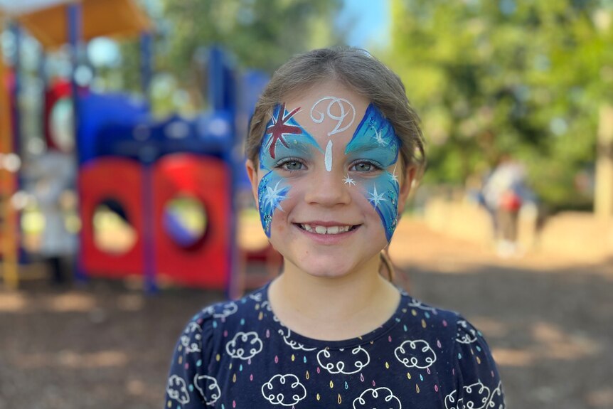 a young girl smiling with an Australian flag face painting