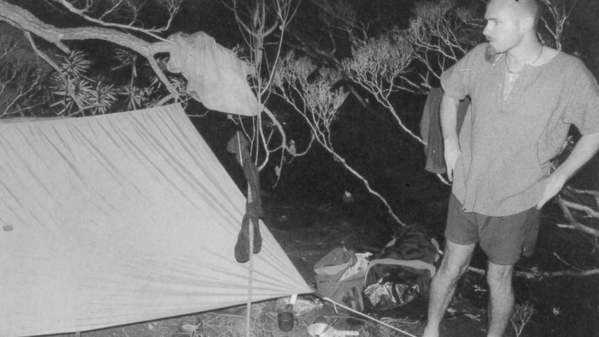 Black and white old photo of young man at camp site