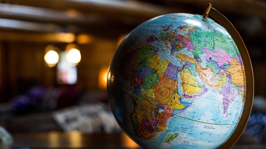 A small globe sits on top of a wooden cabinet in a shadowy room