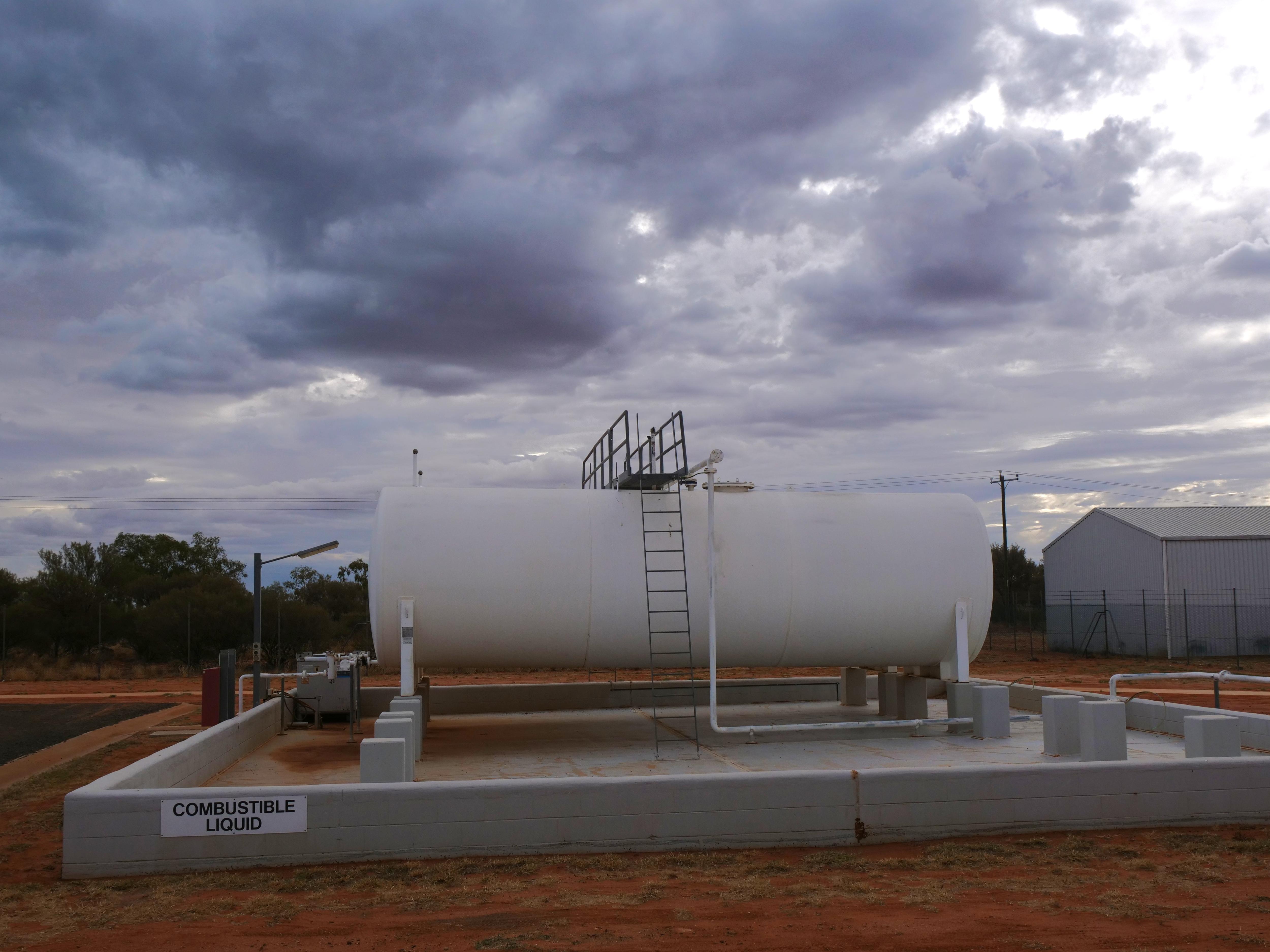 Large white fuel storage tank sits outside. 