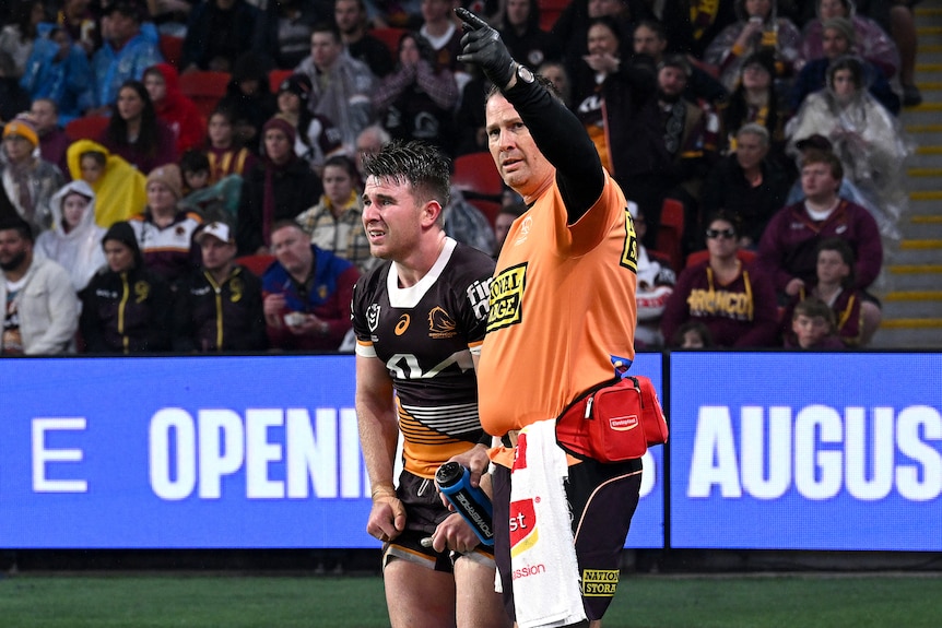 Brisbane Broncos halfback Jock Madden is seen to by a trainer after an injury in an NRL game.