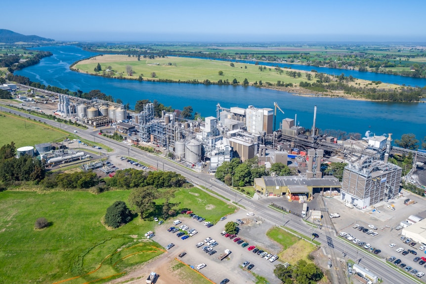 An aerial of a busy manufacturing plant beside a large waterway.