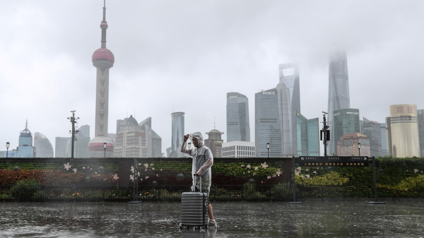 A man with luggage walks in the rain on The Bund as Typhoon In-fa approaches Shanghai
