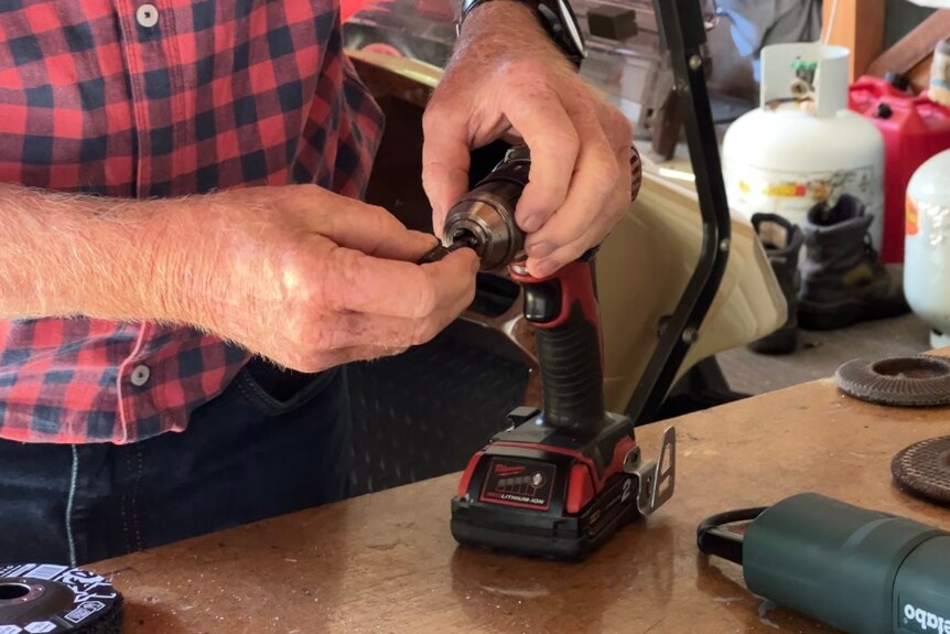 Close up shot of a man changing screws on his power drill 