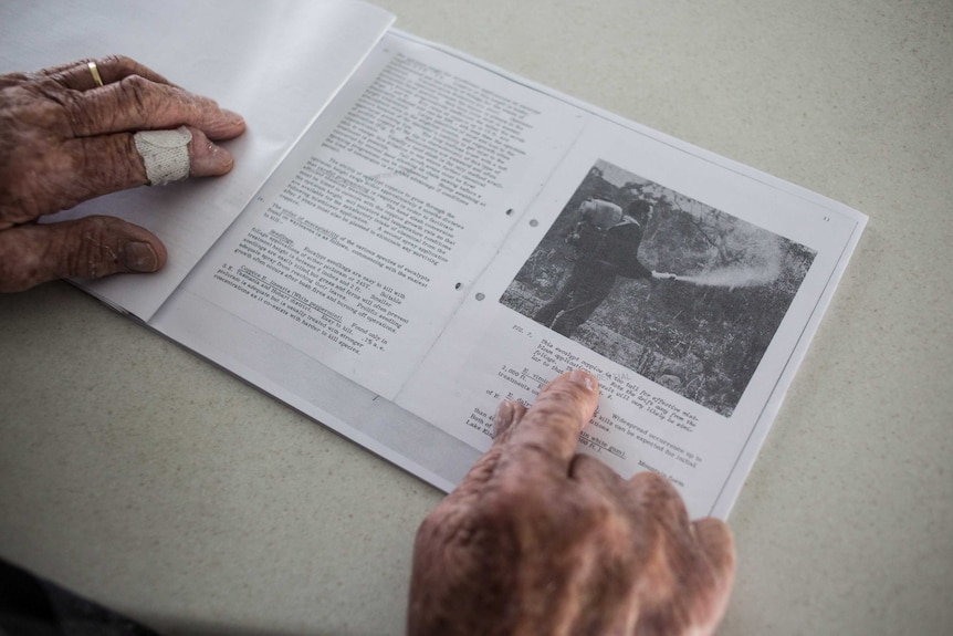 Mr Pratts hands on the report, it is photocopied and in black and white.