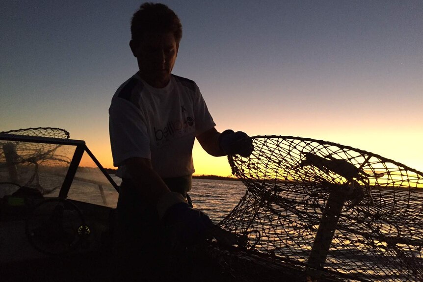 Damien Bell fishes for crabs at sunset.