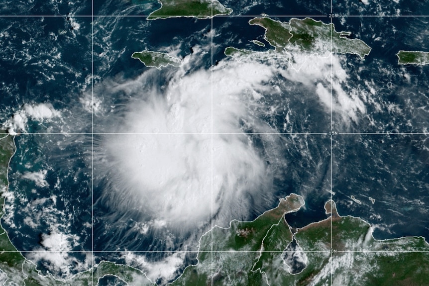 A white, loosely spiralling tropical storm can be seen on a grid map of the Caribbean.