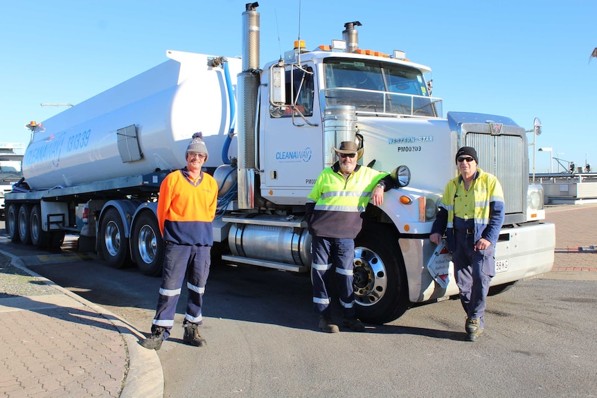 A white haulage truck with three men standing in front of it