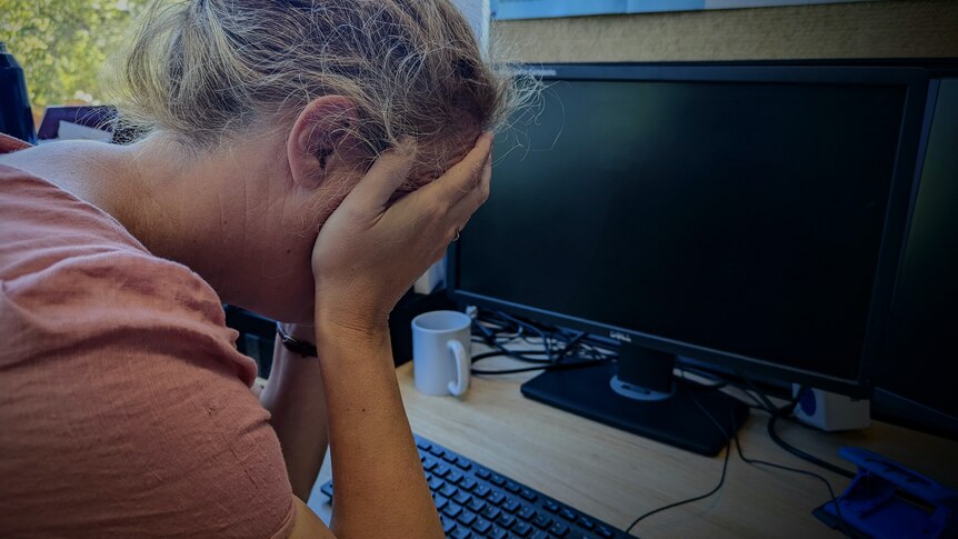 Woman with head in her hands at desk in office