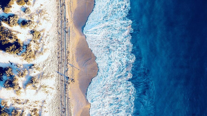 A drone photo of sand dunes, beach and ocean.