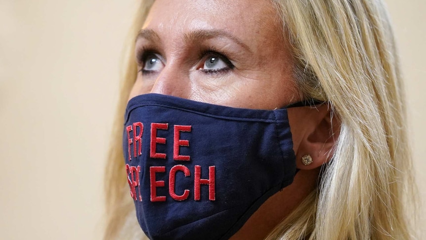 a close up photo of Marjorie Taylor Greene wearing a blue mask with FREE SPEECH written across it