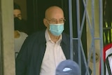 a man in a surgical mask walking out
