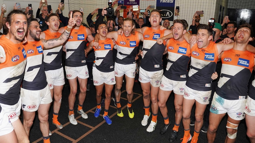 A group of AFL teammates roar out the team song after winning a big final.