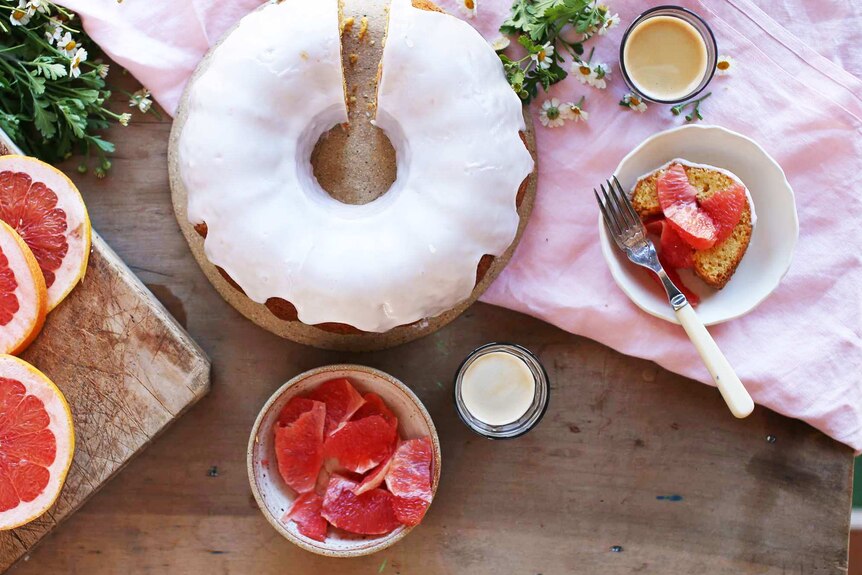 An overhead shot of a bundt cake surrounded by a plate of sliced grapefruit and coffee, illustrating our simple recipe.