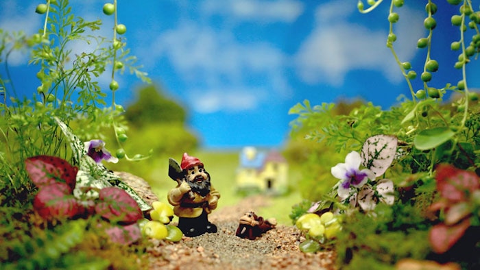 Diorama of a garden scene with miniature gnome and monkey figurine
