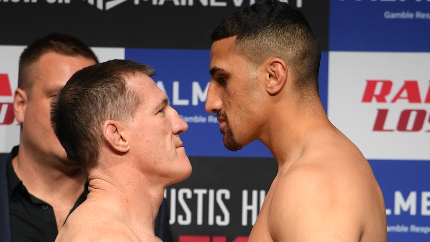 Two heavyweight boxers stand closer to each other as they stare off at a weigh-in.