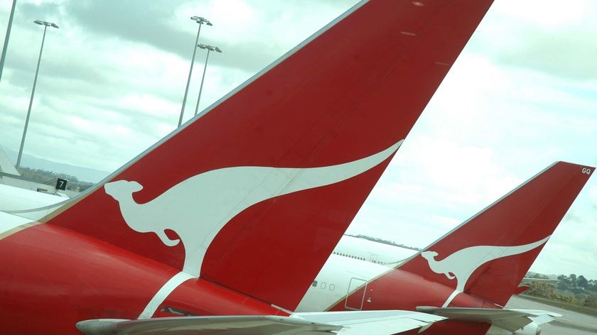 A close-up photo of the tails of two Qantas planes, with a white kangaroo emblem on a red background.