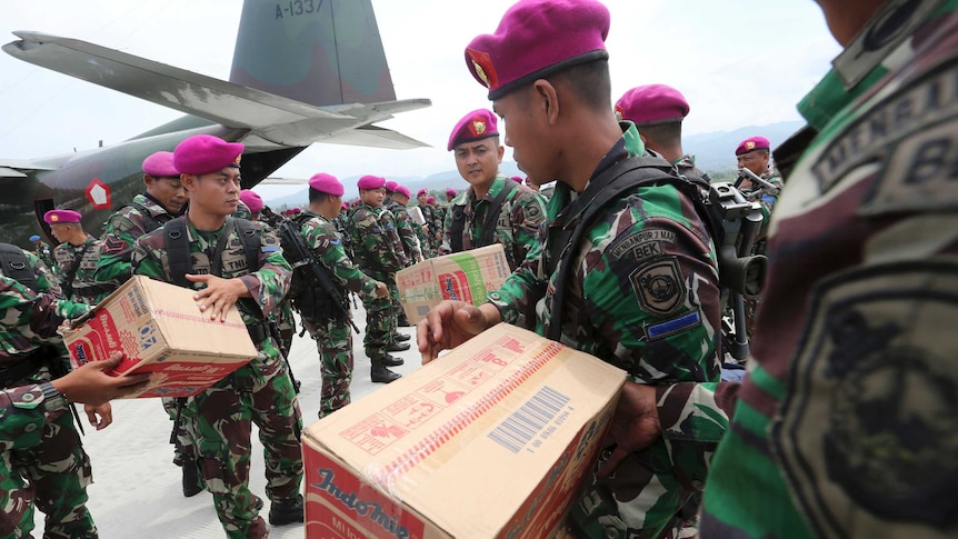 Indonesian military personnel distribute relief aid at Palu's airport.