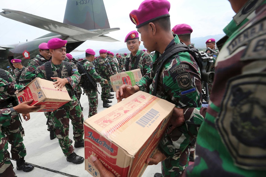 Indonesian military personnel distribute relief aid at Palu's airport.