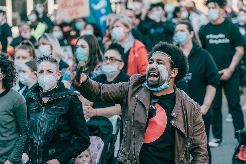 protesters with masks standing with a man yelling in the foreground