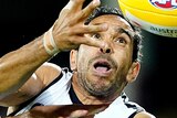 Eddie Betts holds his hands out and looks at a yellow AFL ball while being challenged by a Suns player