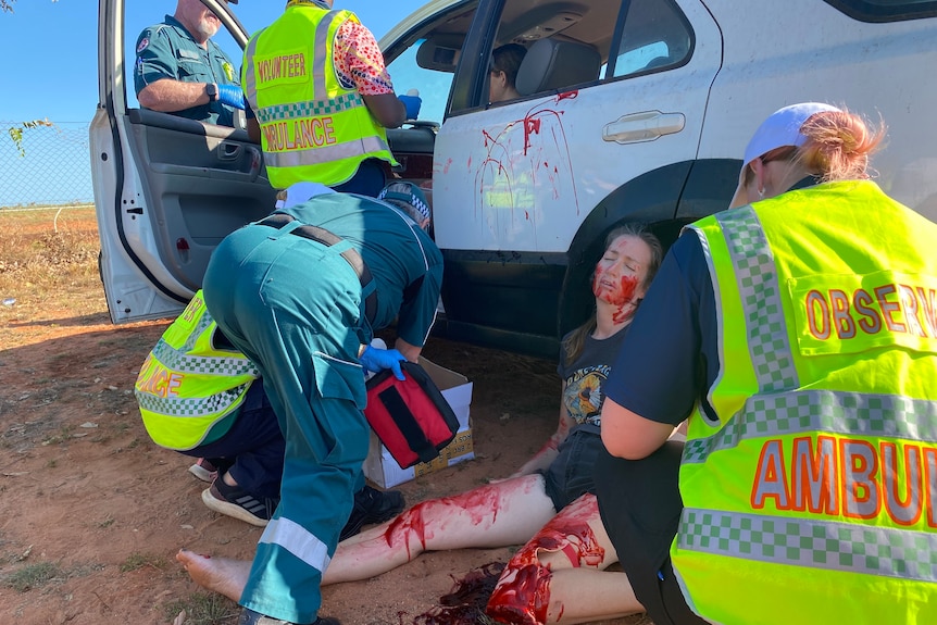 Ambulance officers attend to the mock patient, who has prosthetic skin and fake blood on her knee