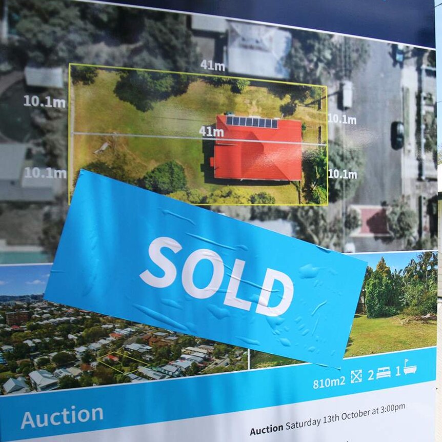 Sold sign on Queenslander-style house in a street in Brisbane.