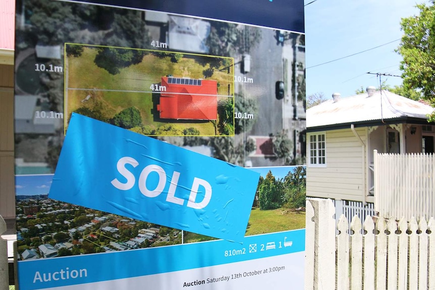 A "sold" sticker on a sale sign out the front of a house.