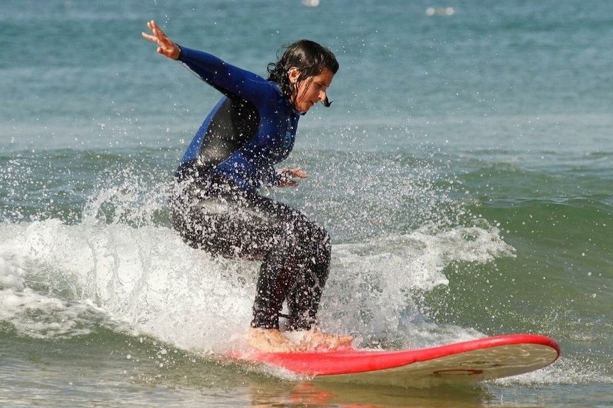 Jess Bart surfing in the waves to depict taking an adult gap year.