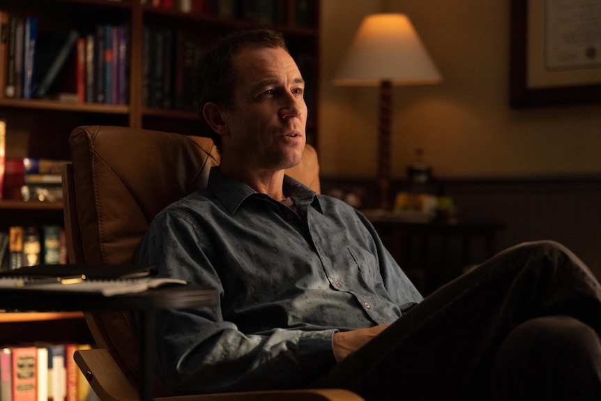 Tobias Menzies, a middle-aged white man with short brown hair, sits in a therapist chair in a warmly-lit room.