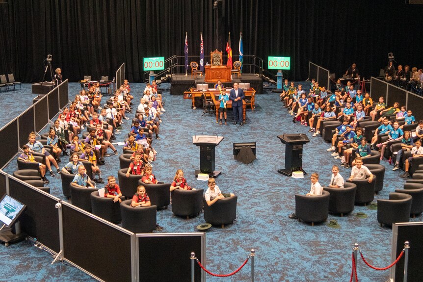 Kids wearing school uniform inside a convention centre at a mock-up parliament sitting.