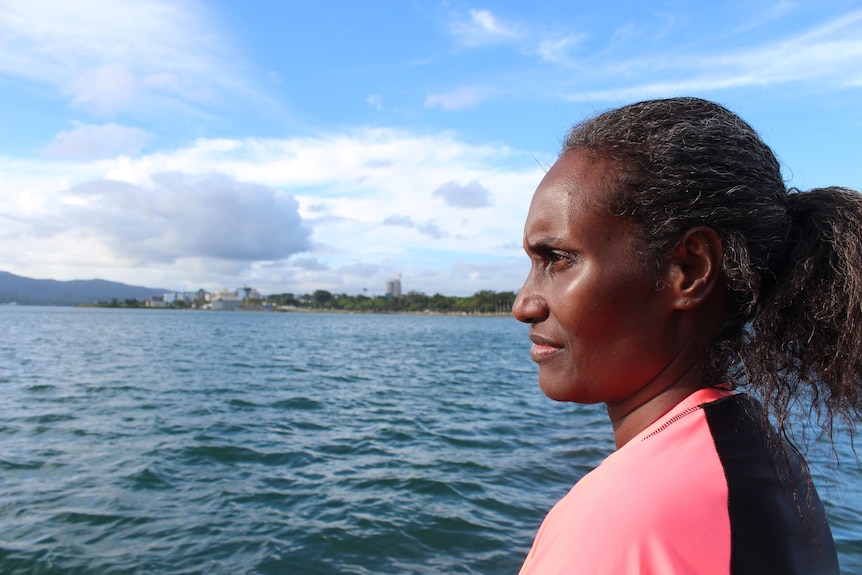 Ocean scientist Dr Katy Soapi in profile on a boat with still water and the coastal edge of Suva behind her