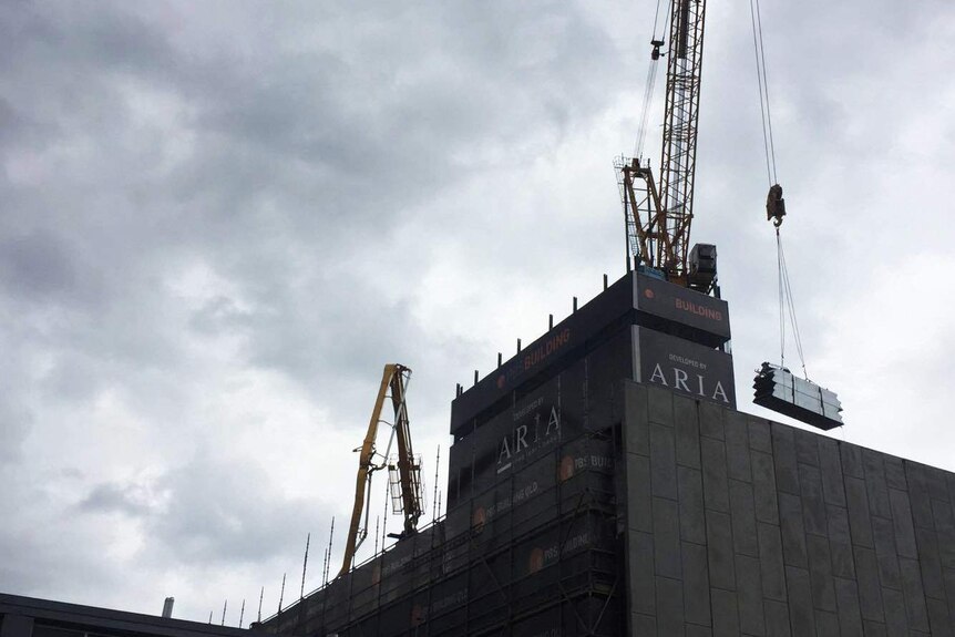 Cranes lift building materials atop a building under construction in Brisbane.