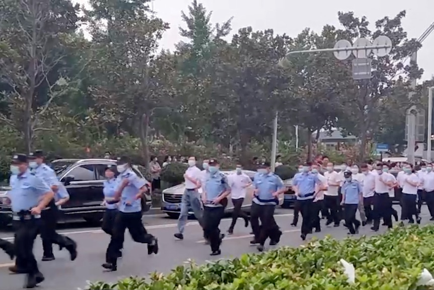 Uniformed and plain-clothed security personnel run in China.